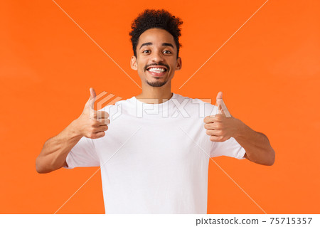 Optimistic, enthusiastic african-american male in white t-shirt, fully agree, feeling happy and satisfied, had great vacation, give positive feedback awesome hotel, showing thumbs-up in approval Optimistic, enthusiastic african-american male in white t-shirt, fully agree, feeling happy and satisfied, had great vacation, give positive feedback awesome hotel, showing thumbs-up in approval 75715357
