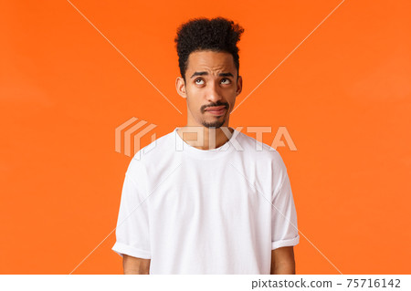 Indecisive and skeptical, gloomy african-american hipster guy with moustache, afro haircut, smirk and looking up unsure, having doubts, dont know how act, standing orange background Indecisive and skeptical, gloomy african-american hipster guy with moustache, afro haircut, smirk and looking up unsure, having doubts, dont know how act, standing orange background 75716142