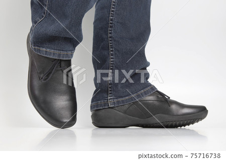 Men's legs in jeans and black classic shoes on white background 75716738