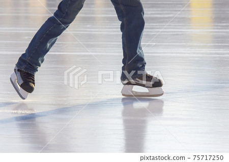 Legs of a man skating on an ice rink. Hobbies and sports. Vacations and winter activities. Legs of a man skating on an ice rink. Hobbies and sports. Vacations and winter activities. 75717250