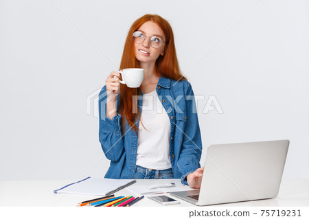 Dreamy, talented good-looking redhead girl studying design and art, looking dreamy and thoughtful up, creating new project, artwork, standing with cup coffee near laptop and pencils 75719231
