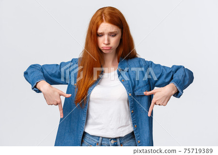 Upset, gloomy timid redhead teenage girl express pity or jealousy, regret something broken, sobbing, pouting sad and looking pointing down distressed, standing unhappy over white background 75719389