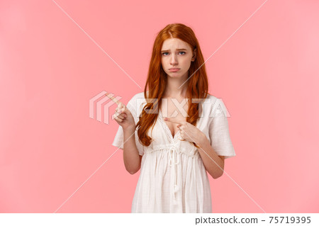 Waist-up portrait gloomy and insecure, upset cute redhead girl, pouting looking distressed or offended, express regret, didnt get present for holiday, pointing finger left, look camera unhappy 75719395