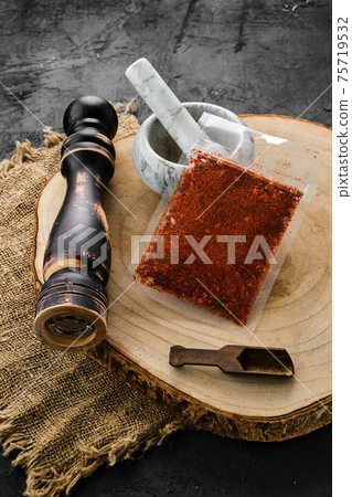Wooden cross section with paprika in plastic package and mortar and mill Wooden cross section with paprika in plastic package and mortar and mill 75719532