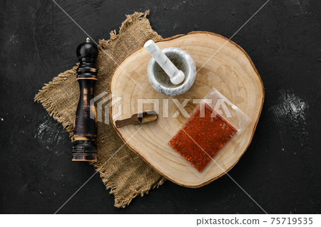Wooden cross section with paprika in plastic package and mortar and mill 75719535