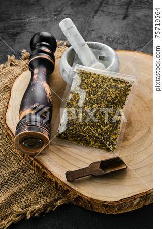 Wooden cross section with lemon pepper in plastic package and mortar and mill 75719564