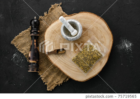 Wooden cross section with lemon pepper in plastic package and mortar and mill 75719565