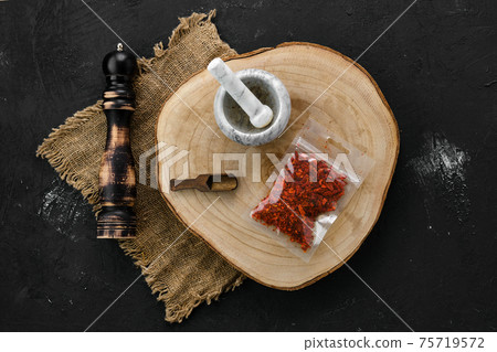 Wooden cross section with crushed paprika in plastic package and mortar and mill 75719572