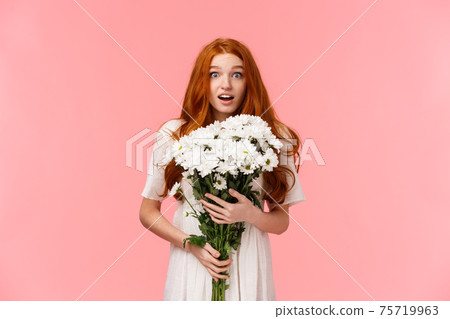 Is it for me. Surprised alluring redhead girl receive unexpected gift, looking amazed and happy, feeling touched, holding beautiful boquet flowers and gazing startled camera, stand pink background Is it for me. Surprised alluring redhead girl receive unexpected gift, looking amazed and happy, feeling touched, holding beautiful boquet flowers and gazing startled camera, stand pink background 75719963