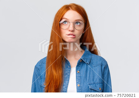 Thoughtful and curious cute redhead teenage girl, thinking, biting lip intrigued and looking up as planning something, recall, pondering between choices, standing white background Thoughtful and curious cute redhead teenage girl, thinking, biting lip intrigued and looking up as planning something, recall, pondering between choices, standing white background 75720021