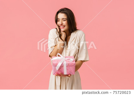 Anticipation, celebration and party concept. Cheerful lovely young woman in dress, cheering close eyes happily smiling and laughing, receiving nice present, got pretty gift, pink background Anticipation, celebration and party concept. Cheerful lovely young woman in dress, cheering close eyes happily smiling and laughing, receiving nice present, got pretty gift, pink background 75720023