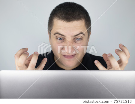 The man looks at the laptop, gets angry and annoyed about what he saw there. Expressing emotions and reacting to what you see on the Internet. Shocking content concept. The man looks at the laptop, gets angry and annoyed about what he saw there. Expressing emotions and reacting to what you see on the Internet. Shocking content concept. 75721513