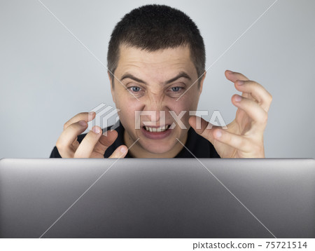 The man looks at the laptop, gets angry and annoyed about what he saw there. Expressing emotions and reacting to what you see on the Internet. Shocking content concept. The man looks at the laptop, gets angry and annoyed about what he saw there. Expressing emotions and reacting to what you see on the Internet. Shocking content concept. 75721514
