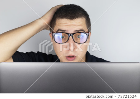 The man looks at the laptop and is frightened by what he saw there. Expressing emotions and reacting to what you see on the Internet. Shocking content concept. The man looks at the laptop and is frightened by what he saw there. Expressing emotions and reacting to what you see on the Internet. Shocking content concept. 75721524