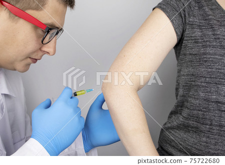 An orthopedic surgeon gives an injection in the elbow. Treatment of osteoarthritis with hormonal drugs or drugs based on hyaluronic acid. Help with diseases that damage the cartilage of the joint 75722680