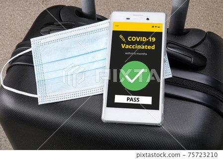 Smartphone with digital vaccination certificate for COVID-19 on a luggage. Smartphone with digital vaccination certificate for COVID-19 on a luggage. 75723210