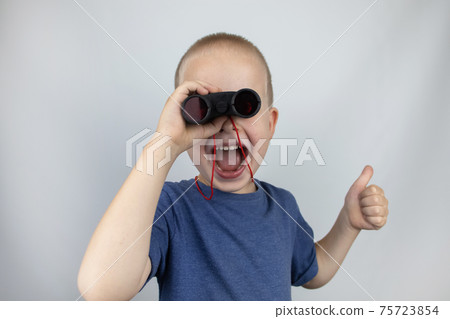 A boy with binoculars looks into the distance and smiles. Facial expression and body position show victory. The concept of vision for success, business confidence and overcoming difficulties. 75723854