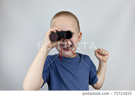 A boy with binoculars looks into the distance and smiles. Facial expression and body position show victory. The concept of vision for success, business confidence and overcoming difficulties. 75723855