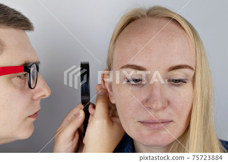 Darwin's tubercle on the ear. The girl at the reception at the plastic surgeon, shows the auricle. Darwin's tubercle on the ear. The girl at the reception at the plastic surgeon, shows the auricle. 75723884