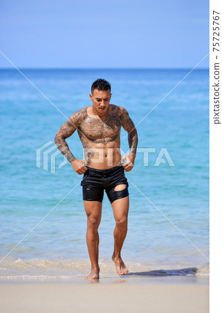 Athletic young tattooed guy at the beach Athletic young tattooed guy at the beach 75725767