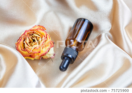 container for storing cosmetics made of dark glass lie on the folds of silk  75725900