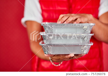 Delivery man in red vest uniform hold go box food, delivery service, isolated on red background Delivery man in red vest uniform hold go box food, delivery service, isolated on red background 75726078