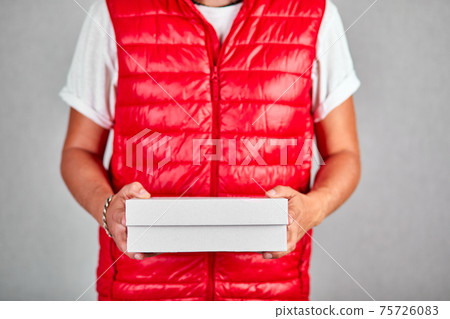 Delivery man employee in red vest uniform hold empty cardboard box Delivery man employee in red vest uniform hold empty cardboard box 75726083