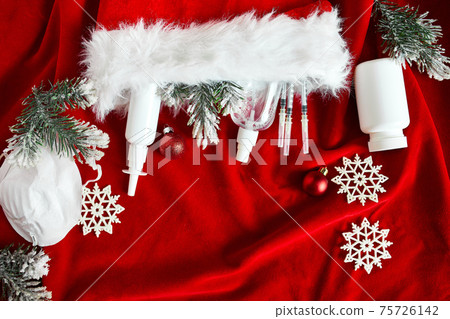 Christmas medical coronavirus flat lay, protective face mask, pills, antiseptics, decoration on red background Christmas medical coronavirus flat lay, protective face mask, pills, antiseptics, decoration on red background 75726142