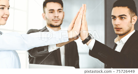 Business people group showing teamwork, joining hands and giving five to each other in modern office. Success concept 75726449