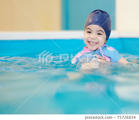 Cheesy smile of girl in swimming pool 75726834