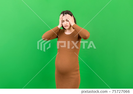 Beautiful young pregnant woman feeling head ache on colored background isolated. Stressed pregnant woman or mother problems Beautiful young pregnant woman feeling head ache on colored background isolated. Stressed pregnant woman or mother problems 75727066