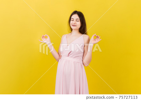 Smiling pregnant woman standing and practicing yoga isolated on colored background Smiling pregnant woman standing and practicing yoga isolated on colored background 75727113