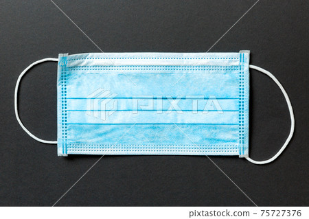 Close up of virus outbreak inscription on stack of medical masks on colored background. Wuhan virus. World epidemic Close up of virus outbreak inscription on stack of medical masks on colored background. Wuhan virus. World epidemic 75727376