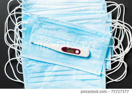 Epidemic background of protective medical masks and a thermometer on colored background. World quarantine concept 75727377