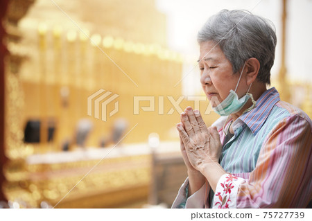 old asian senior woman traveler tourist praying at buddhist temple. old asian senior woman traveler tourist praying at buddhist temple. 75727739