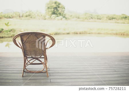 wicker rattan chair on balcony terrace patio near pond 75728211