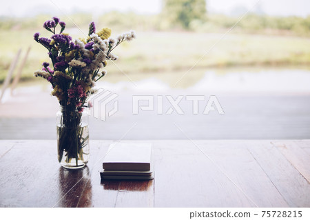 flower bouquet in glass vase and book at patio flower bouquet in glass vase and book at patio 75728215