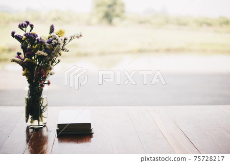 flower bouquet in glass vase and book at patio 75728217