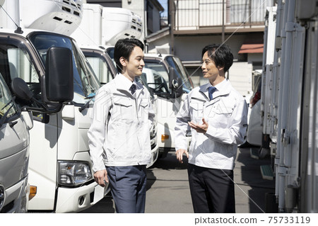 一個男人走在卡車之間交談時 一個男人走在卡車之間交談時 75733119