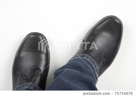 Men's legs in jeans and black classic shoes on white background 75734870