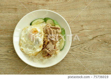 fried slice pork meat with garlic and pepper topping egg on plain rice in plate 75736019