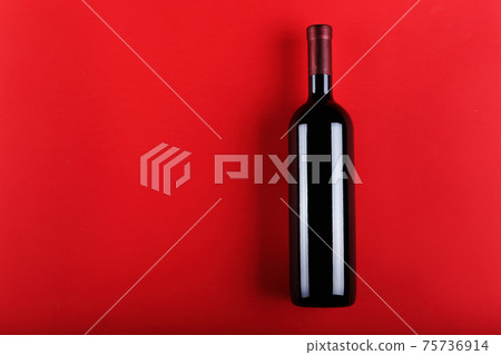 Wine bottle on a red paper background. 75736914