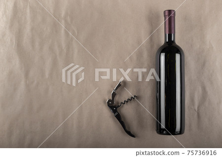 Wine bottle and corkscrew on a brown background. Space for text. 75736916