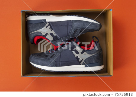 Pair of sneakers in a shop box on a orange background. 75736918