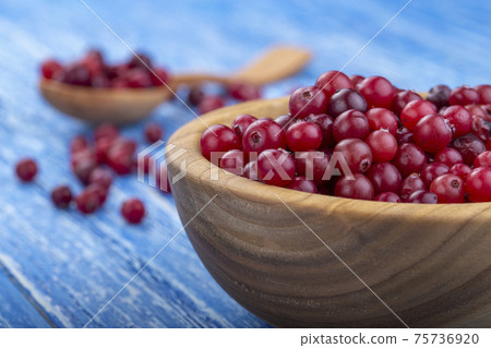 Fresh cranberries in a bowl on a wooden table. 75736920