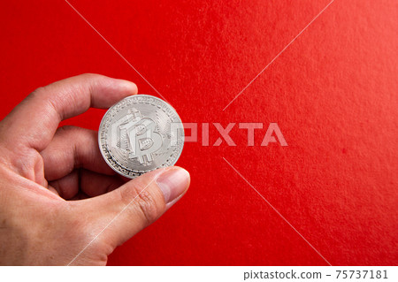 Hand holding a bitcoin on red background 75737181
