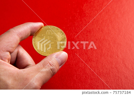 Hand holding a bitcoin on red background Hand holding a bitcoin on red background 75737184