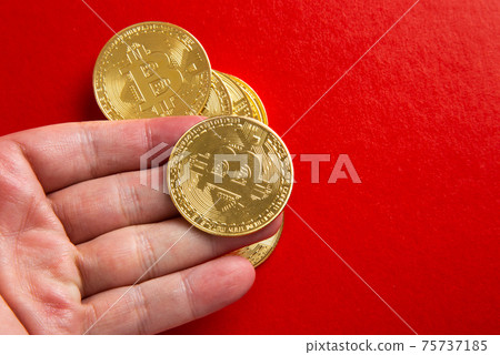 Hand holding a bitcoin on red background 75737185