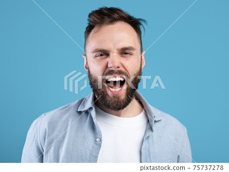 Enraged bearded guy shouting in anger, expressing his aggression over blue studio background Enraged bearded guy shouting in anger, expressing his aggression over blue studio background 75737278