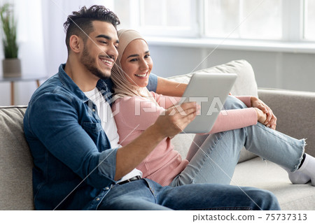 Cheerful arab guy showing something girlfriend on Internet, using pad 75737313